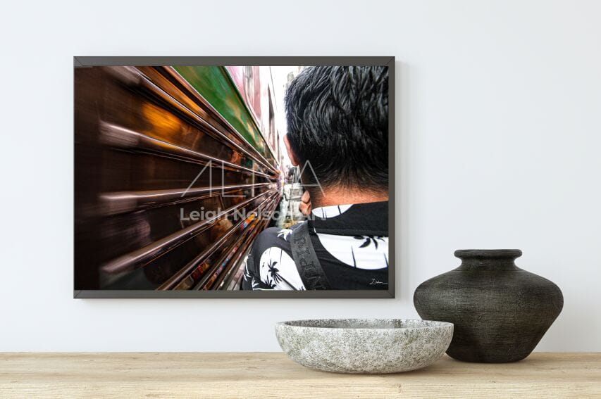 Framed artwork of a person looking at a train, displayed on a wall with decorative items below. Wall Paintings